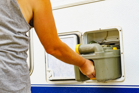 Man takes holding tank of a camping toilet from the mobile home