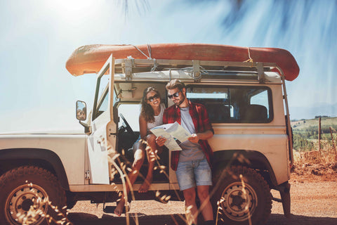 Couple on road trip studying map on car