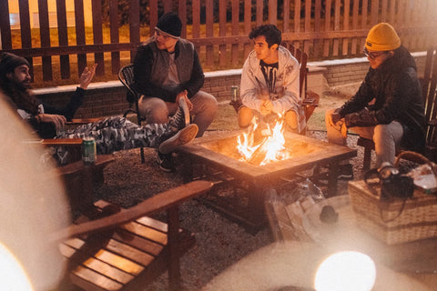 Noite masculina no jardim do loteamento: os homens sentam-se confortavelmente à volta da fogueira com uma cerveja. 