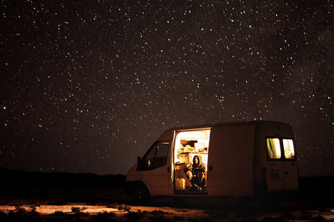 Autocamper med lys under en stjernehimmel
