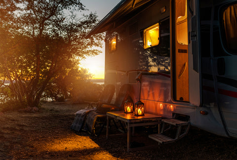 Camping chairs and table in front of a mobile home in the sunset