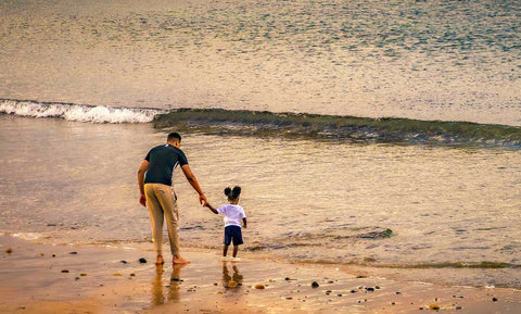 Vater mit Tochter am Strand, in den Wellen spielend