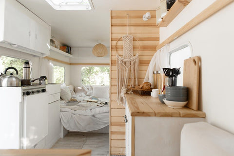 Chic white interior of a mobile home with kitchen and bed