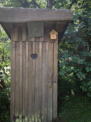 Casa de banho de jardim com um coração fresado na porta - um lugar bonito e tranquilo no campo. 