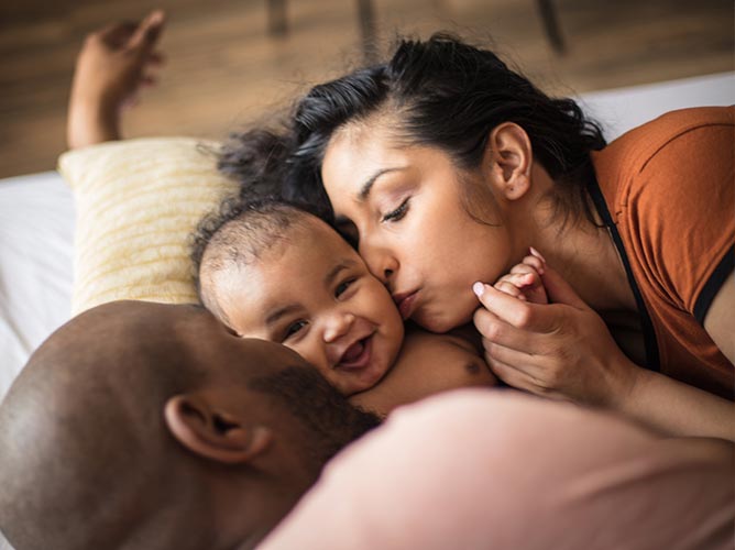 New mother and father cuddling with their newborn child.