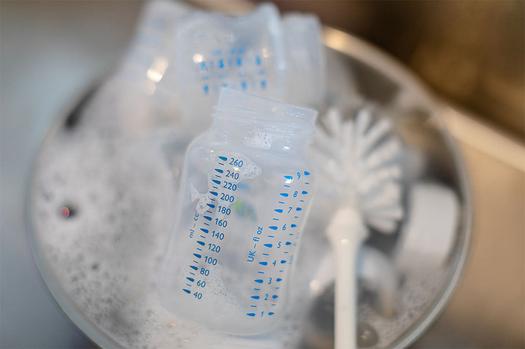 Bowl filled with warm, soapy water and soaking baby bottles.