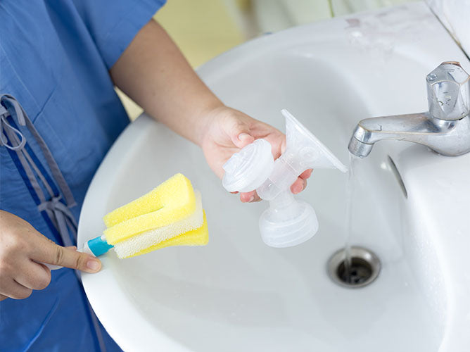 Person washing parts of a breast pump in the sink.