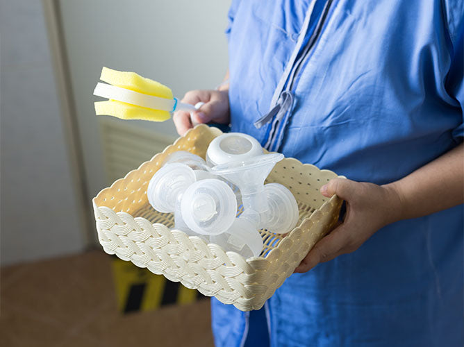 Person about to clean breast pump parts in a sink.