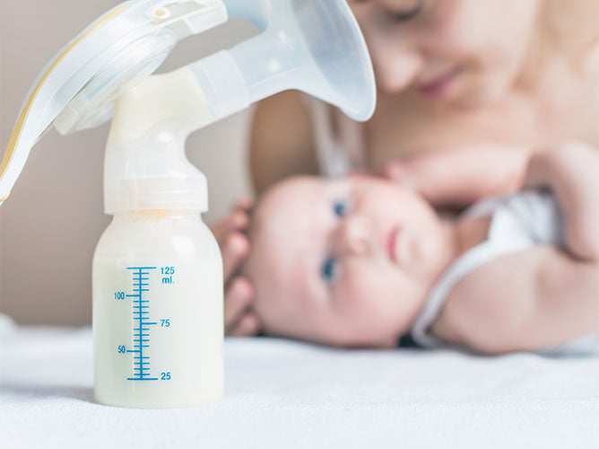 Closeup of newly pumped breast milk next to a newborn baby.
