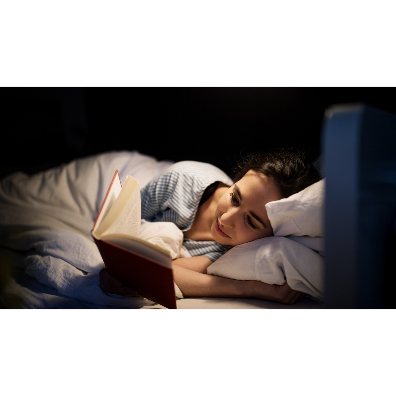 Une femme lit un livre avant de dormi
