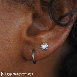 Ear pierced with with a White Opal Ti Sun Cabochon