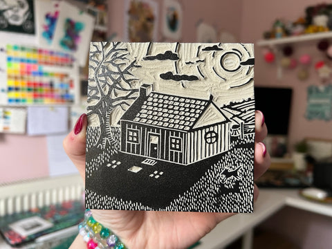 A small 10cm x 10cm lino block of a small house and tree