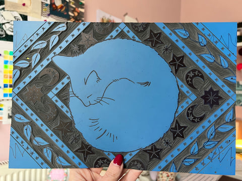 The finished lino block of a cat sleeping on a rug