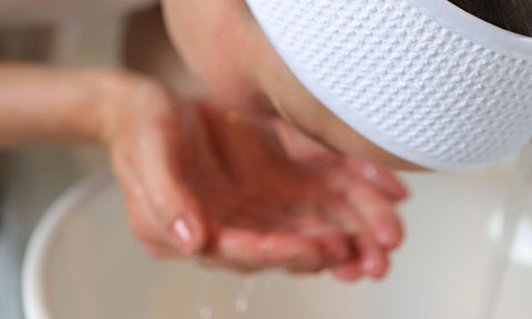 kvinna tvättar sitt ansikte under rinnande vatten