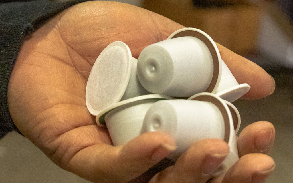 A Metropolis Coffee roaster holds six nitrogen-flushed coffee capsules in their hand.