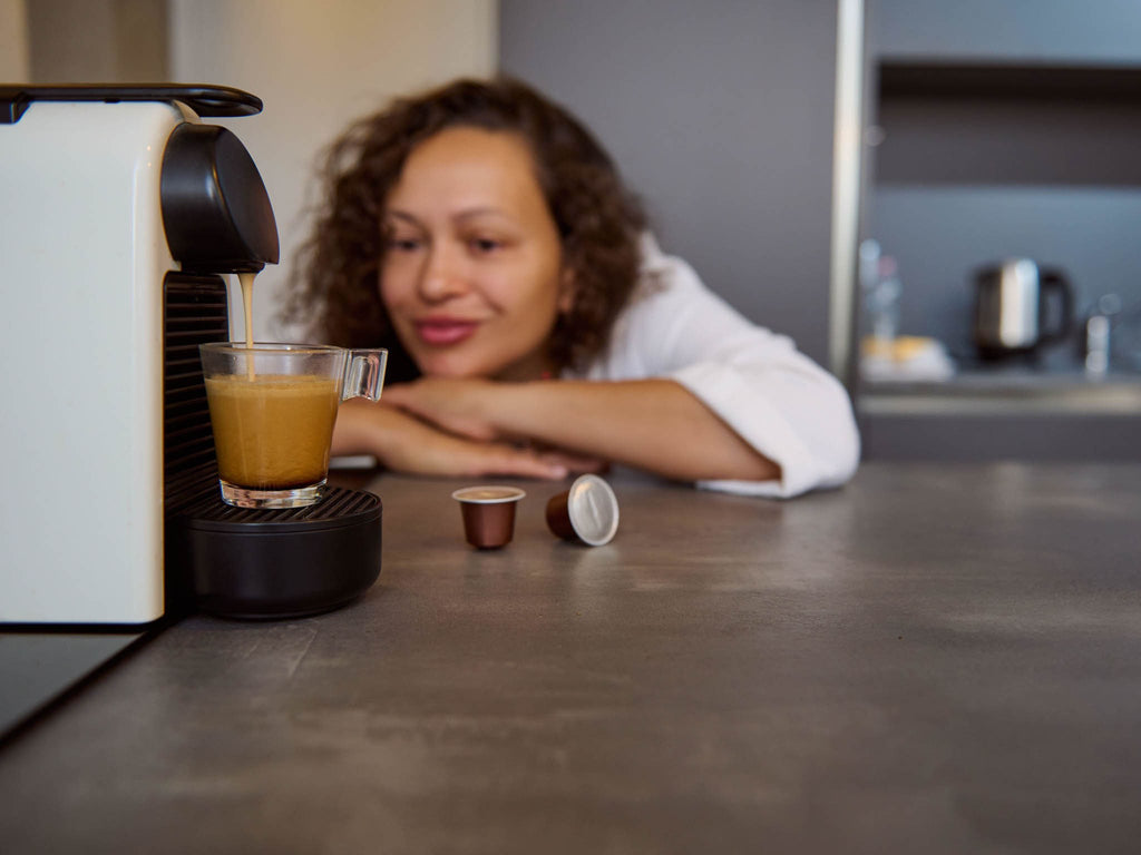 A woman waits for her espresso-style coffee to brew.