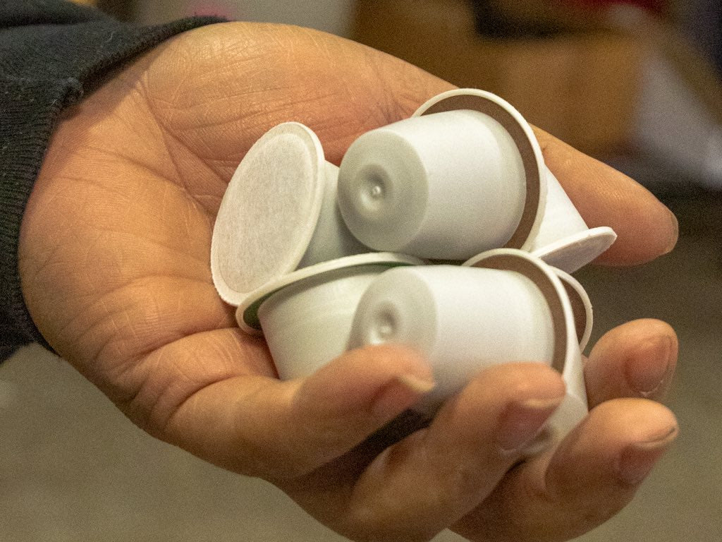 A person holds private label coffee capsules in their left hand.