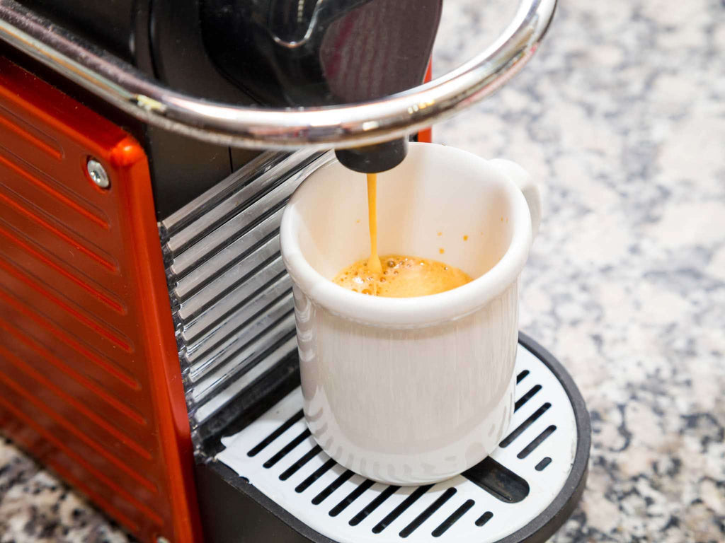 A Nespresso original line coffee brewer brews a wholesale coffee capsule.