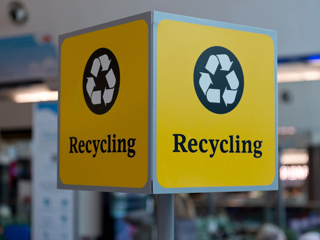 A recycling sign hanging above private label coffee capsules.