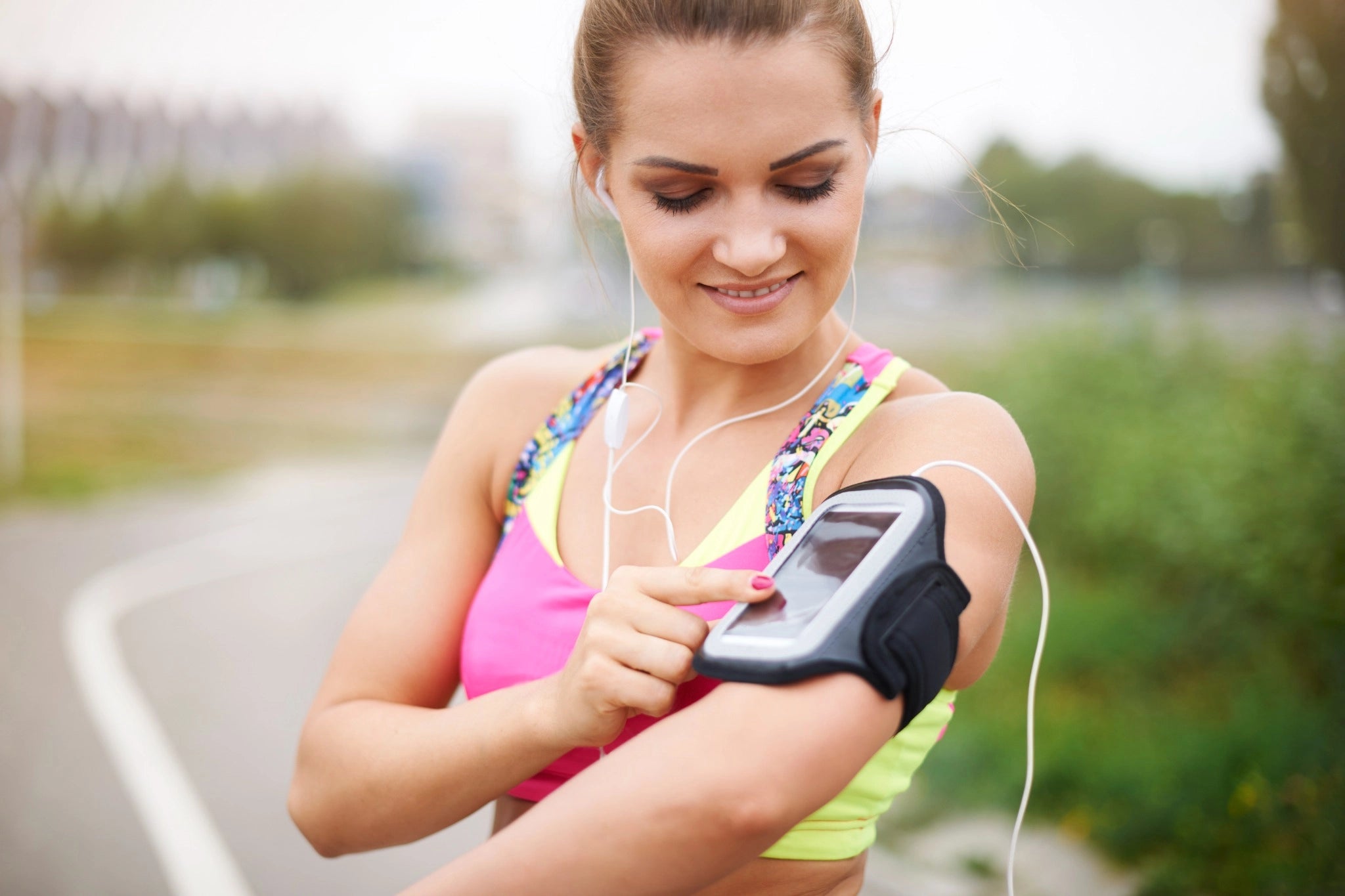 Runner using a smartphone armband to monitor heart rate during her recovery run after half marathon, easing back into activity.
