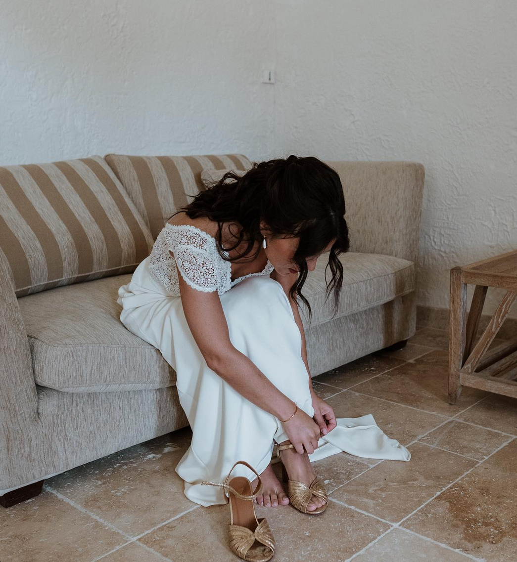 une mariée ferme ses souliers de mariage dorés, escarpins ouverts