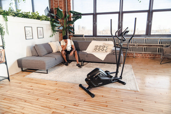 man sitting on couch after workout on an elliptical machine