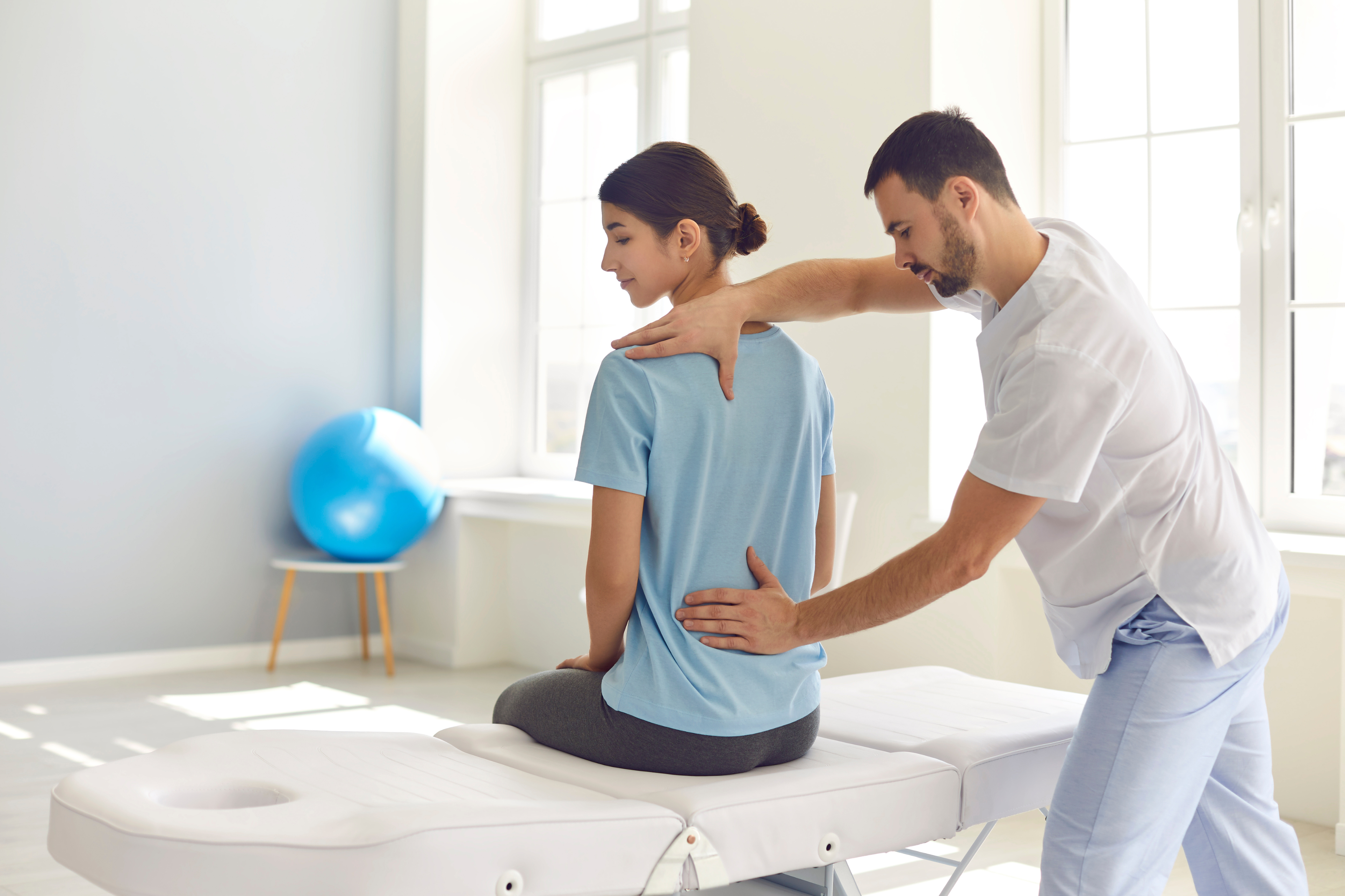 A doctor or physical therapist working with a patient on their posture