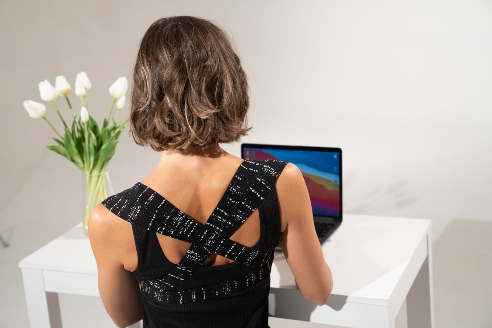 A person wearing a posture corrector while sitting at a desk