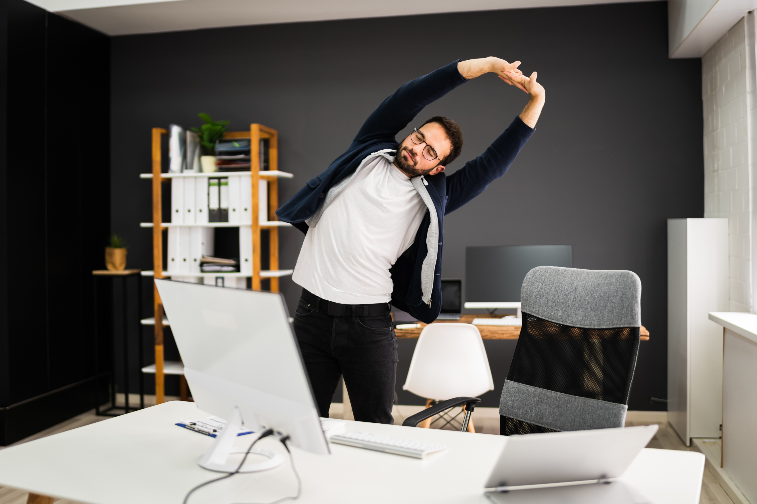 A person stretching beside their desk