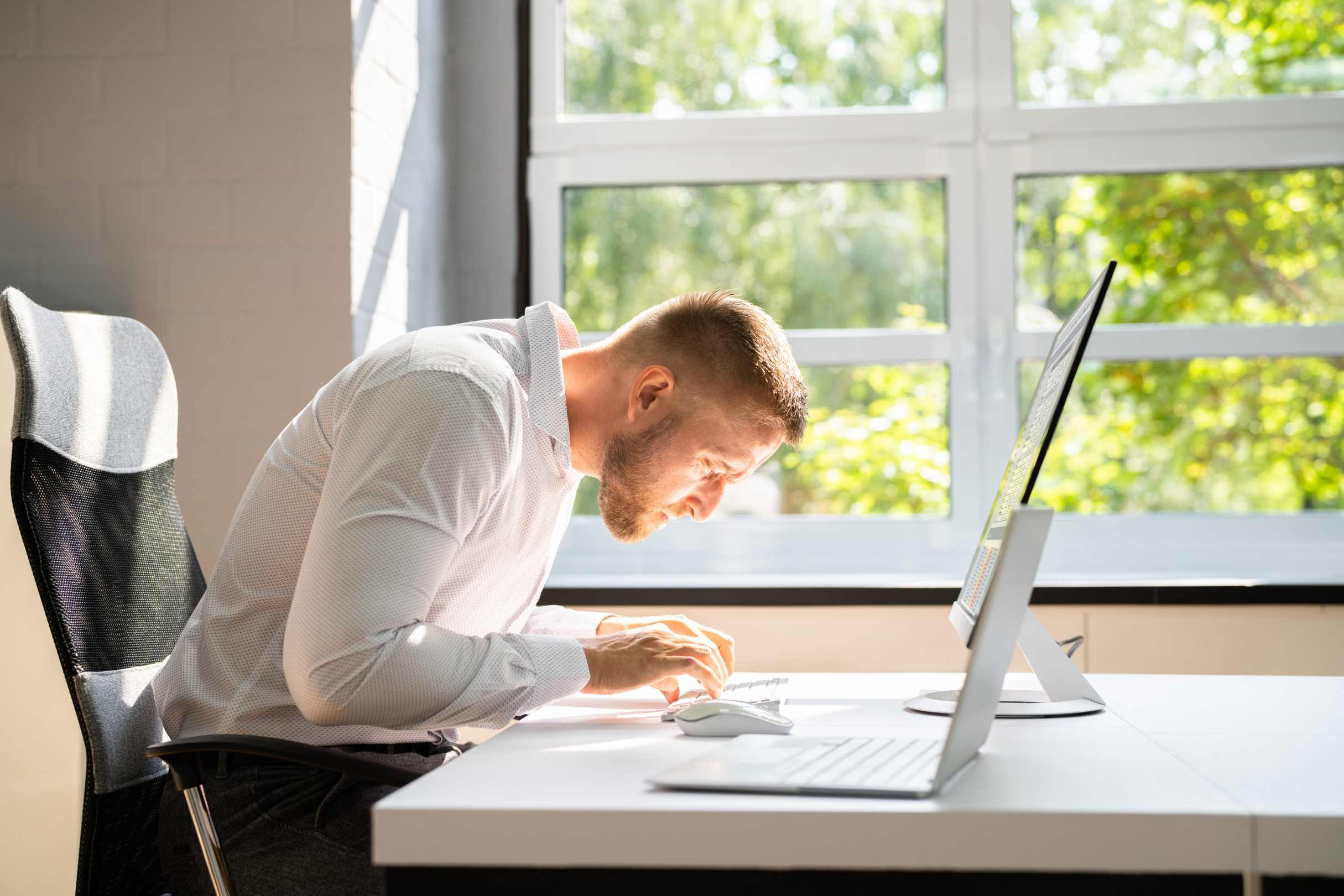 Someone craning their neck down to type on a laptop.