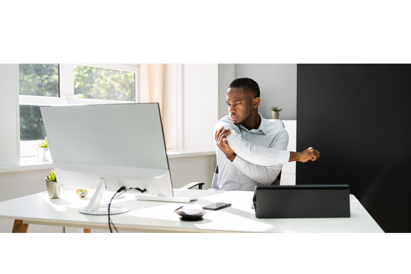 A person at a standing desk (perhaps wearing a posture corrector)