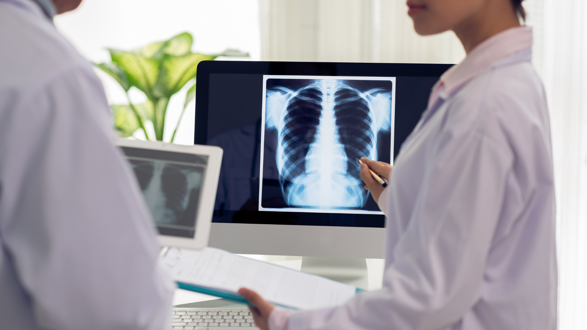 A doctor pointing to an X-ray of a spine