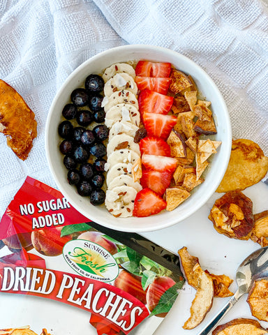 Dried and fresh fruit in a bowl with a snack-sized bag of Sunrise Fresh dried peaches