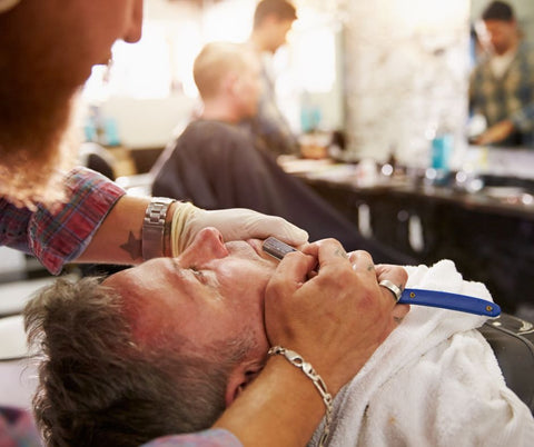 Barber giving a cut throat shave with a straight razor