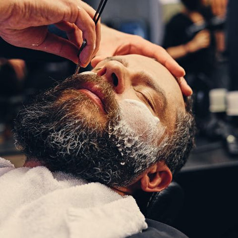 barber giving a straight razor shave to customer