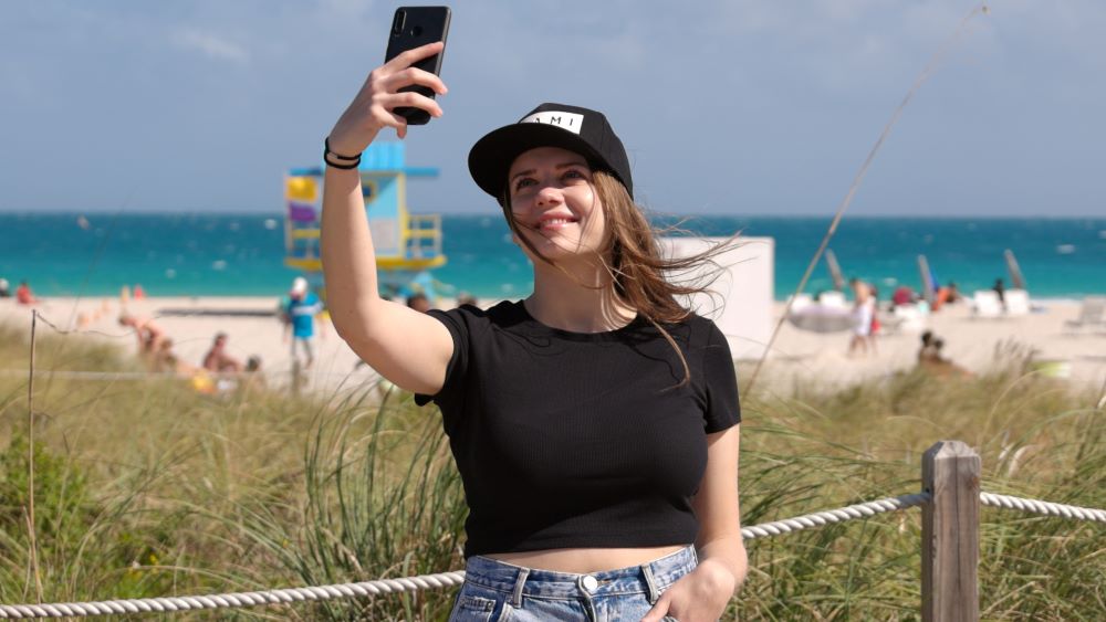 Beautiful young woman in South Beach takes a selfie on the beach