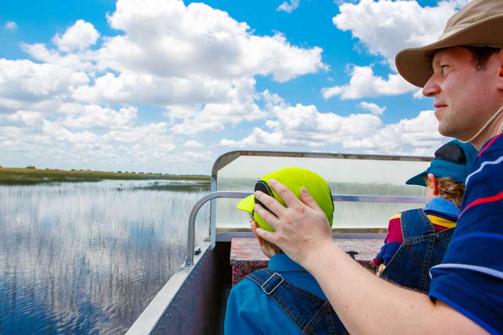 Two little kids boys and father making air boat tour in Florida wetland swamp at Everglades National Park