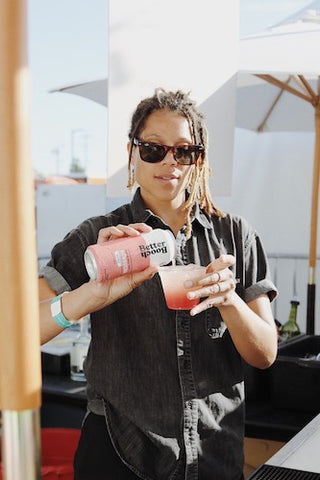 Woman wearing sunglasses pouring Better Booch kombucha into a cup