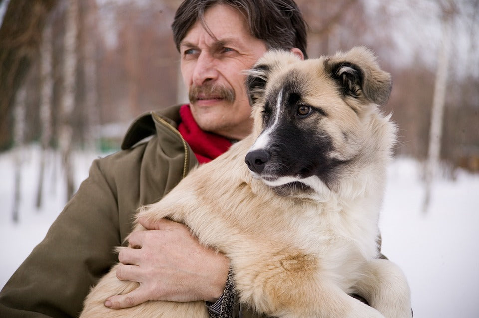 Ein Mann hält einen Hund.