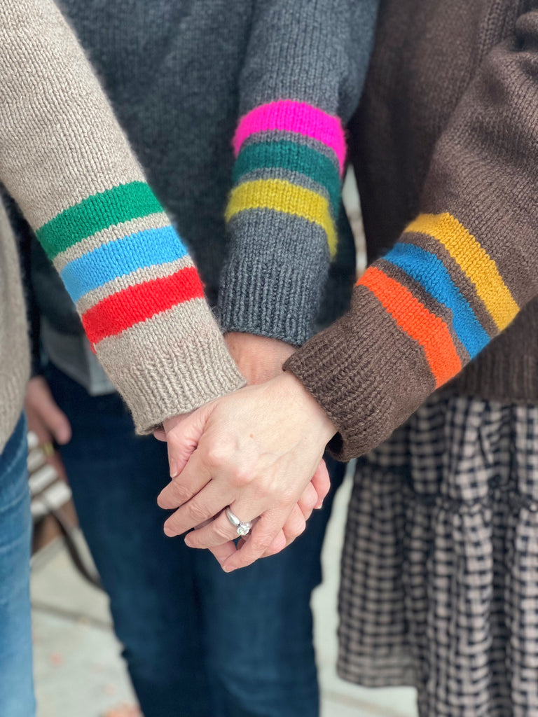 Three Varsity Sweater clad arms with hands clasped.