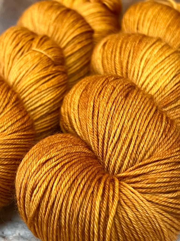 A close up of two skeins of orange yarn.