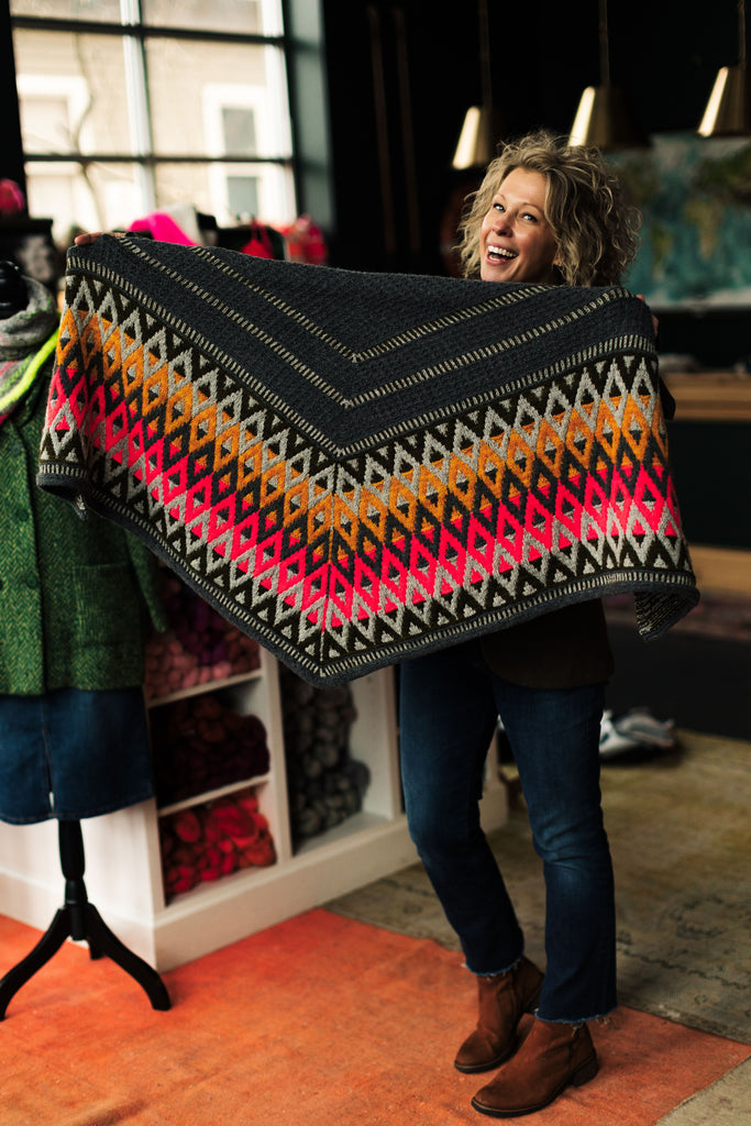 Sarah holding out an Artus Shawl wide to show off the colors and motifs.