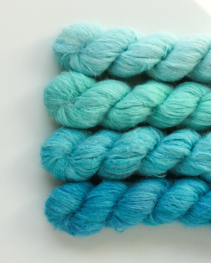 Four skeins of yarn in icy blue shades.