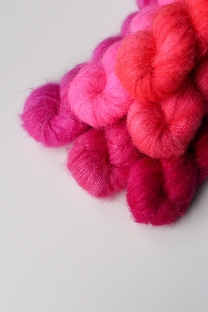 A pyramid of six skeins of bright pink yarn.