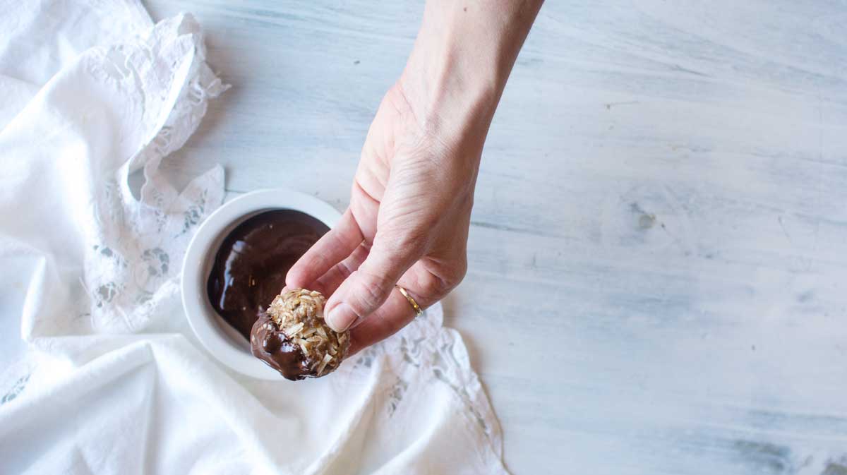 Dipping cannabis infused peppermint coconut date balls into dark chocolate