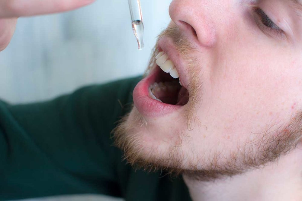 Man dropping CBD tincture under his tongue 