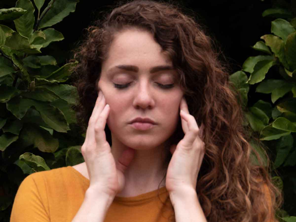 Woman massaging clenched jaw while stressed