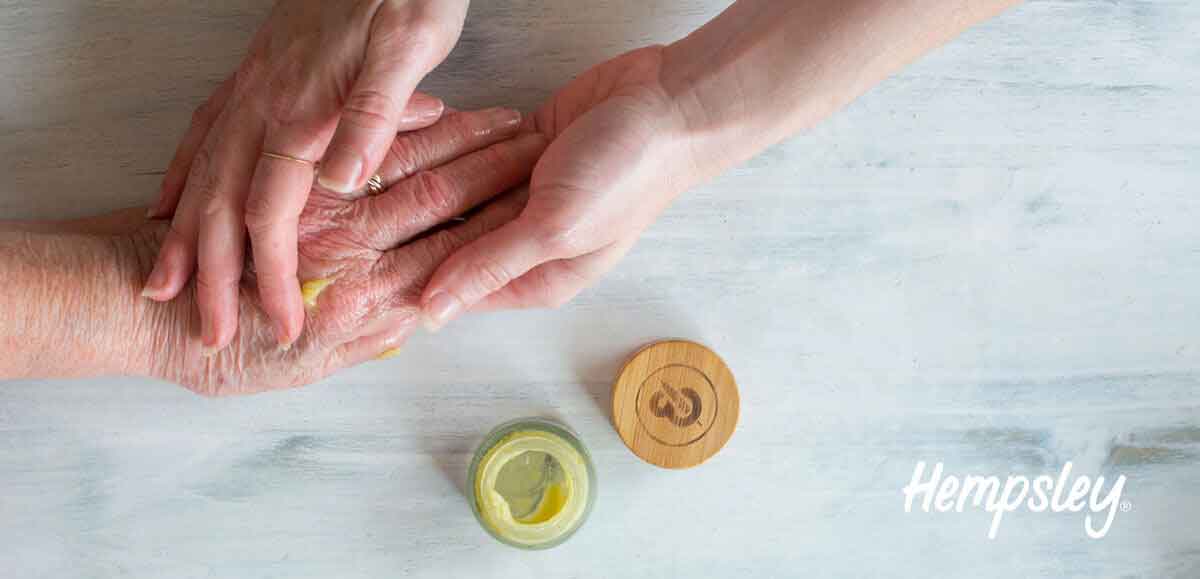 Young woman rubbing her grandmother's hands with Papa and Barkley's CBD Releaf Balm