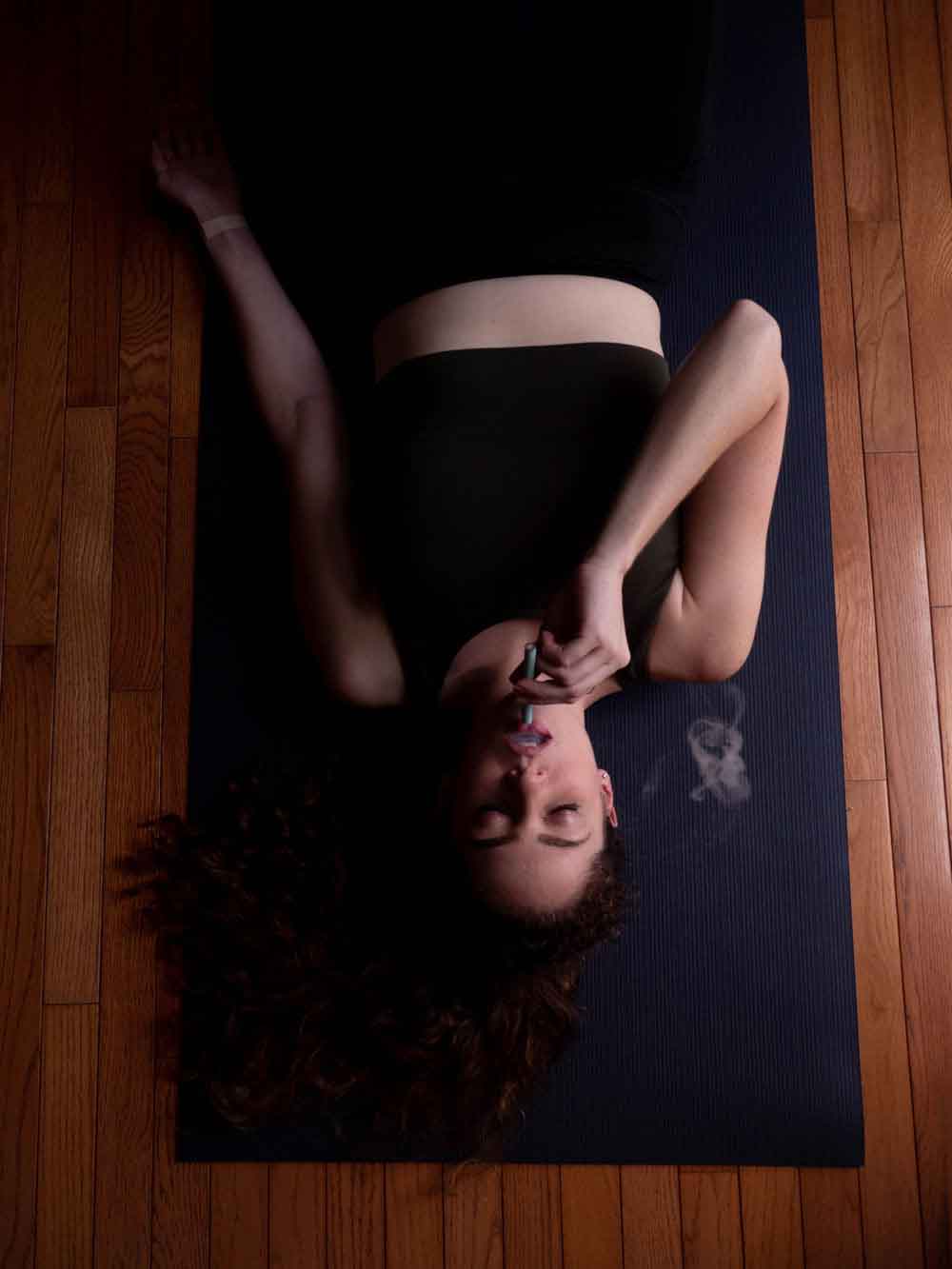 Woman vaporizing cannabis while doing yoga to support her endocannabinoid system through exercise