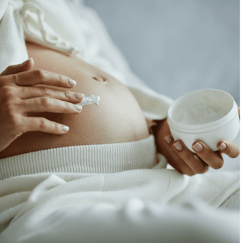 donna che spalma crema rassodante per pancia dopo il parto